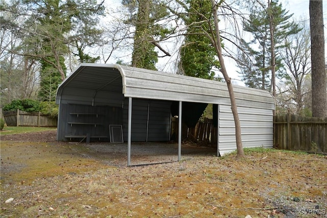 view of outdoor structure featuring fence and a detached carport