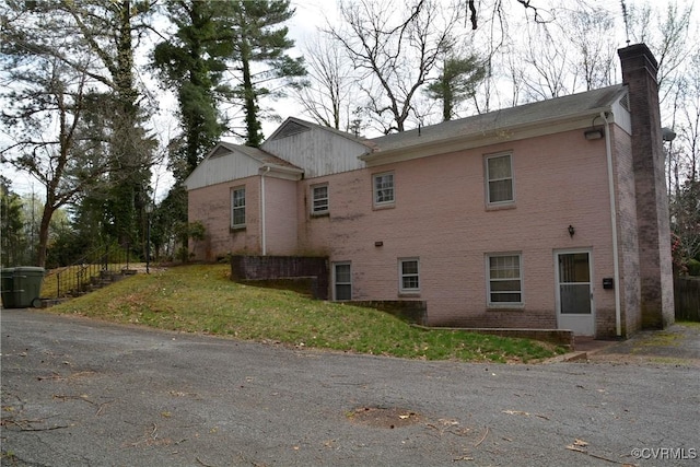 view of side of property featuring a chimney and brick siding