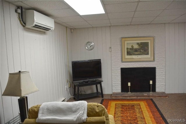 carpeted living area with an AC wall unit, a drop ceiling, a fireplace, and wooden walls