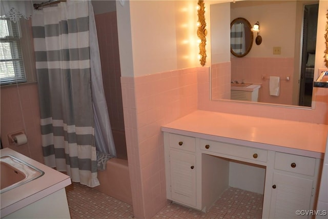 full bath with tile walls, vanity, wainscoting, and shower / bath combo