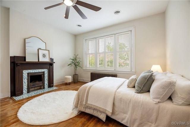 2706 W Grace St, Richmond, VA 23220 - bedroom with radiator heating unit, wood finished floors, baseboards, and a fireplace with flush hearth