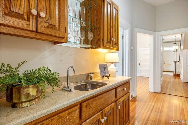2706 W Grace St, Richmond, VA 23220 - kitchen featuring a sink, brown cabinetry, light wood-style flooring, and light stone counters