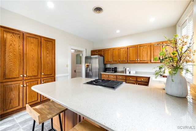 2706 W Grace St, Richmond, VA 23220 - kitchen with stainless steel appliances, a peninsula, brown cabinetry, a kitchen breakfast bar, and recessed lighting