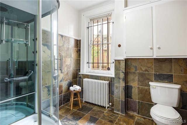 2706 W Grace St, Richmond, VA 23220 - bathroom with radiator, tile walls, a shower stall, toilet, and stone finish floors