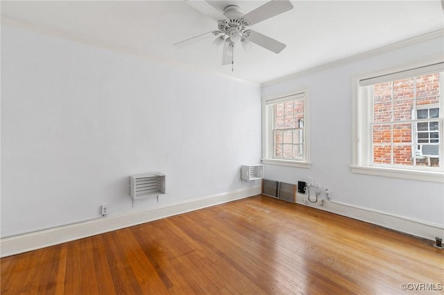 spare room featuring crown molding, ceiling fan, a wall mounted air conditioner, wood finished floors, and baseboards