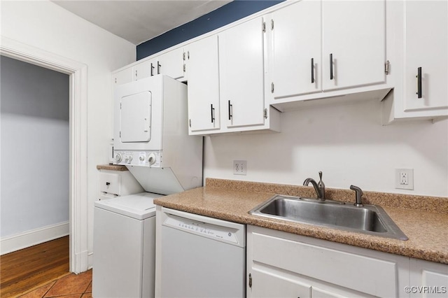 laundry area with stacked washer and clothes dryer, a sink, baseboards, and tile patterned flooring