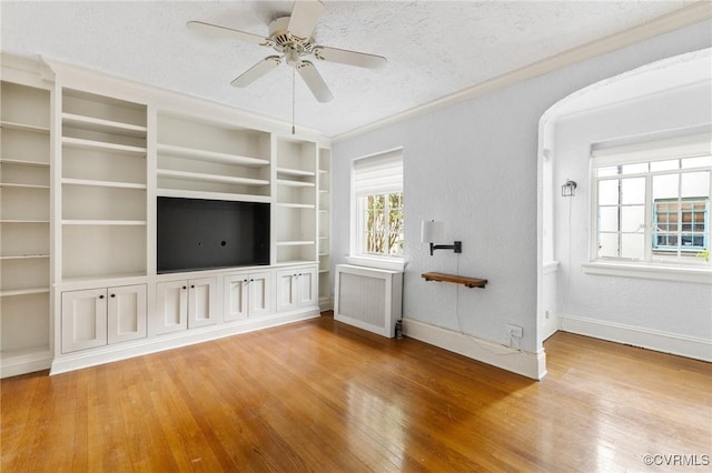 unfurnished living room featuring radiator heating unit, wood-type flooring, baseboards, ceiling fan, and a textured ceiling