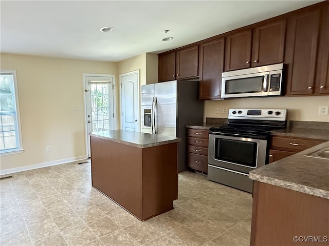 3000 Perdue Springs Ln, Chester, VA 23831 - kitchen with appliances with stainless steel finishes, a kitchen island, dark brown cabinetry, dark countertops, and baseboards