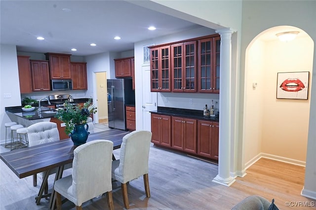 5801 Riverside Trl, Richmond, VA 23225 - kitchen with appliances with stainless steel finishes, dark countertops, baseboards, reddish brown cabinets, and arched walkways