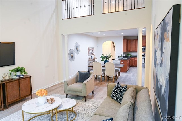 5801 Riverside Trl, Richmond, VA 23225 - living area featuring ornate columns, a towering ceiling, light wood-style flooring, arched walkways, and baseboards