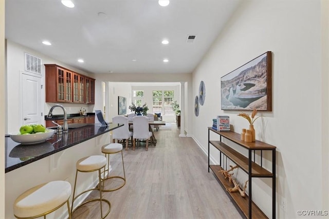 5801 Riverside Trl, Richmond, VA 23225 - kitchen featuring recessed lighting, a sink, light wood-style flooring, a breakfast bar area, and glass insert cabinets