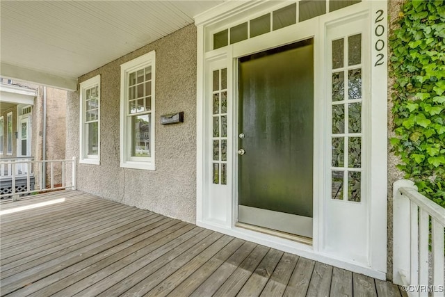 entrance to property with a porch and stucco siding