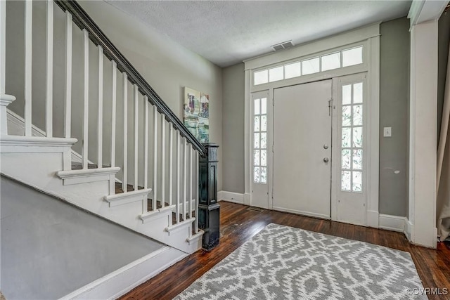 entryway featuring stairs, wood-type flooring, baseboards, and a textured ceiling