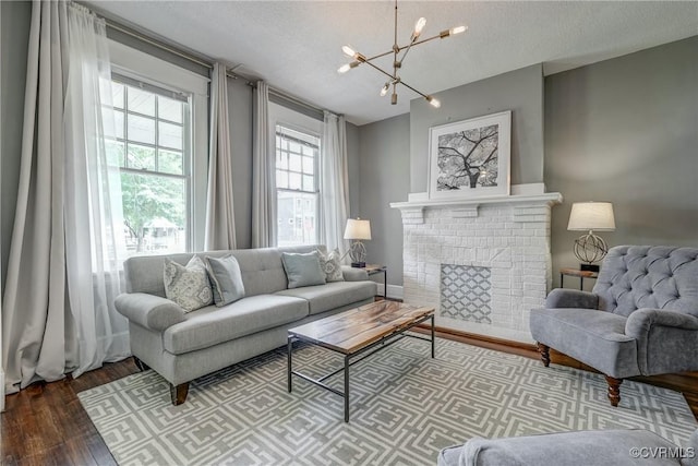 living room featuring a chandelier, wood finished floors, a fireplace, and a textured ceiling