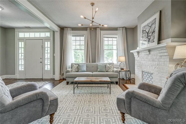 living room with a chandelier, a textured ceiling, wood finished floors, and baseboards