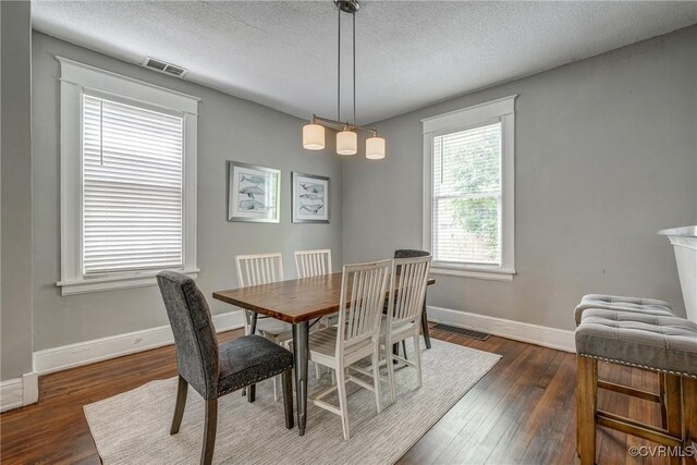 dining area featuring dark wood-type flooring, a textured ceiling, and baseboards