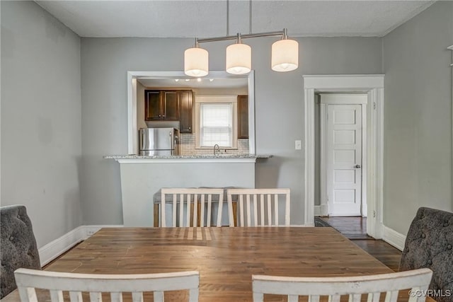 dining area with baseboards and dark wood finished floors