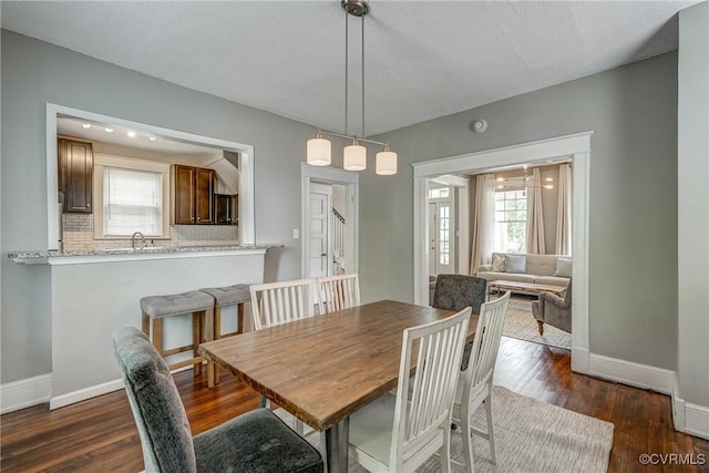 dining area with baseboards, healthy amount of natural light, and dark wood-type flooring