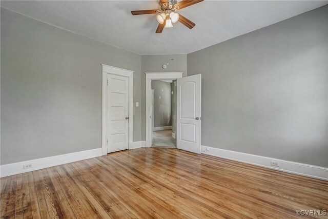 unfurnished room with a ceiling fan, baseboards, and light wood-style flooring
