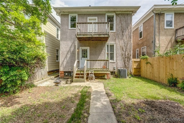 back of house featuring a balcony, central air condition unit, and stucco siding