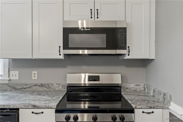 kitchen featuring stainless steel appliances, white cabinetry, and light stone countertops