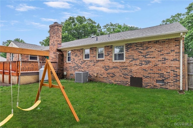 back of property with cooling unit, a wooden deck, brick siding, and a yard