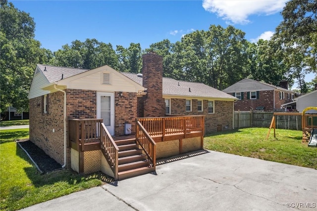 rear view of house with a patio, a wooden deck, brick siding, a chimney, and a playground