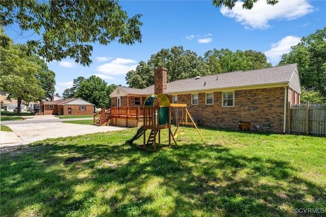 rear view of property featuring a playground, brick siding, a chimney, driveway, and an attached garage