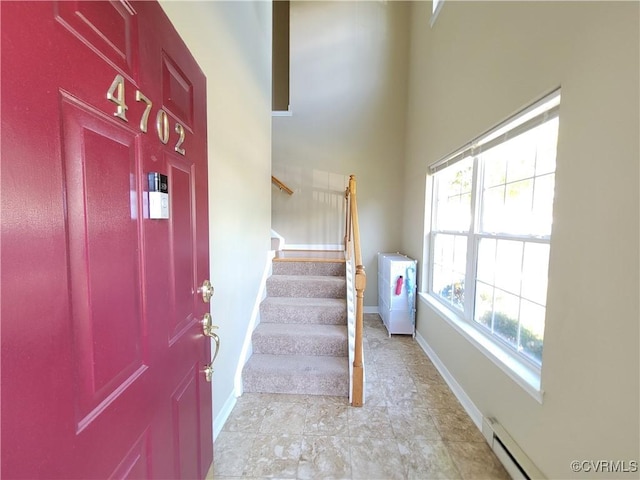 foyer entrance featuring baseboards, stairs, and a baseboard radiator