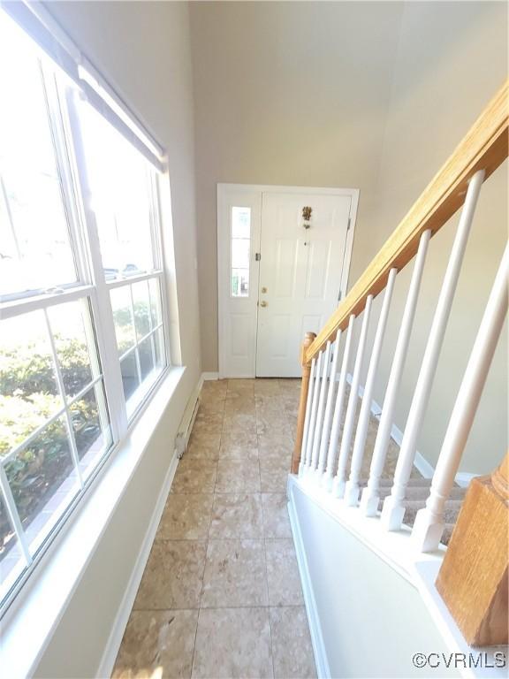 entryway featuring baseboards, stairway, and a high ceiling