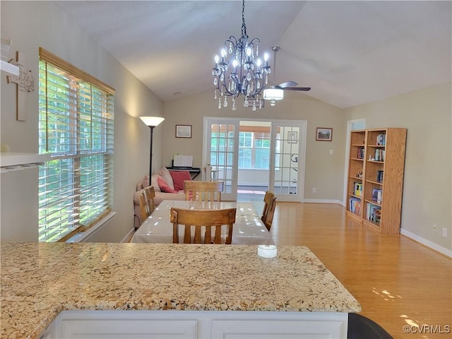 kitchen with vaulted ceiling, light wood finished floors, a chandelier, open floor plan, and white cabinetry