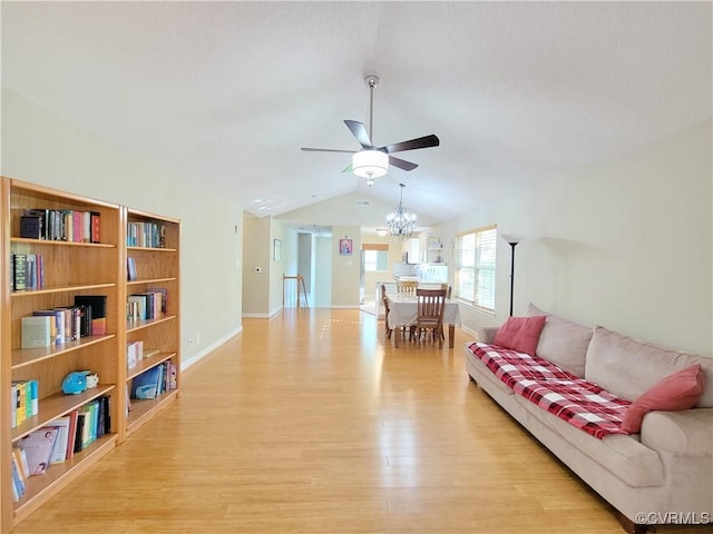 living room featuring a ceiling fan, light wood finished floors, vaulted ceiling, a chandelier, and baseboards