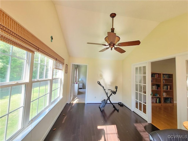exercise room featuring lofted ceiling, dark wood finished floors, a ceiling fan, and baseboards