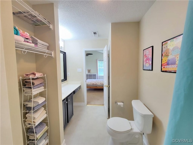 ensuite bathroom with toilet, a textured ceiling, and vanity