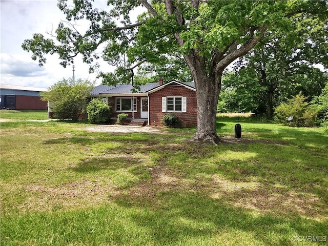 single story home featuring a chimney, brick siding, a front lawn, and metal roof