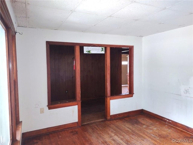 unfurnished room with baseboards, hardwood / wood-style flooring, and a paneled ceiling