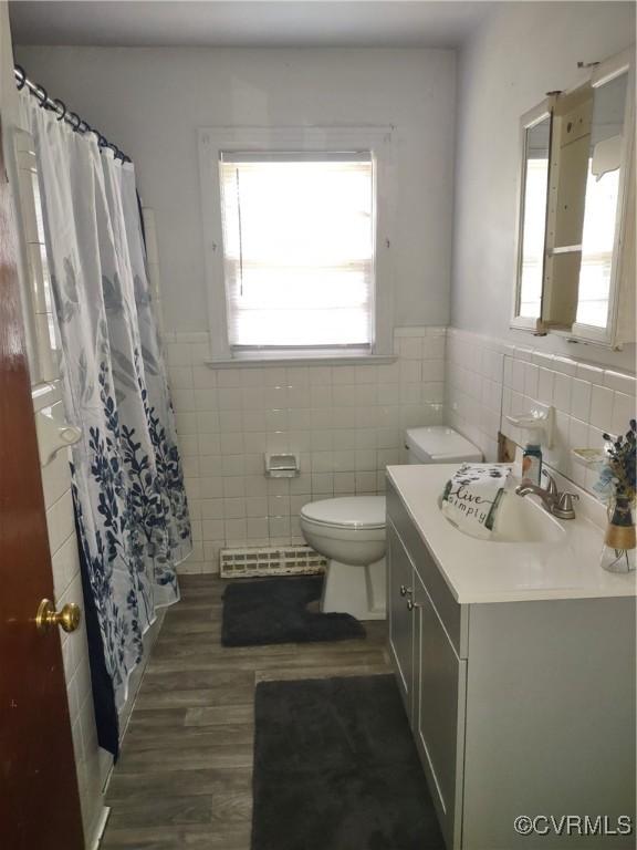 bathroom with tile walls, toilet, vanity, wood finished floors, and a wainscoted wall