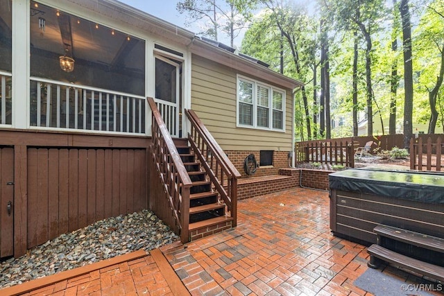 view of patio with a hot tub, stairway, a sunroom, and fence
