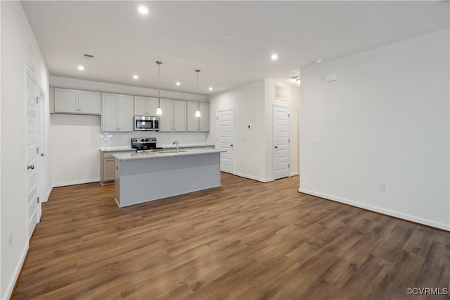 kitchen featuring appliances with stainless steel finishes, a sink, recessed lighting, a kitchen island with sink, and baseboards