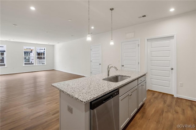 kitchen with stainless steel dishwasher, a sink, wood finished floors, hanging light fixtures, and light stone counters