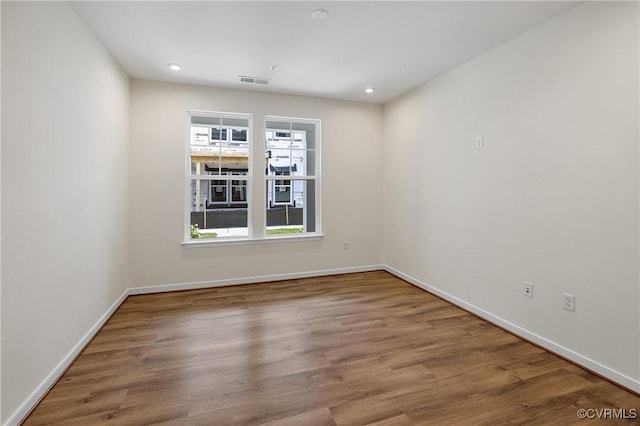 empty room featuring wood finished floors, baseboards, and recessed lighting