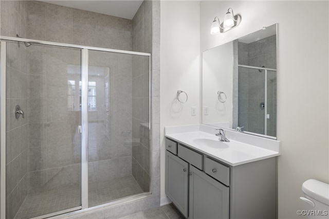 bathroom with toilet, a stall shower, and vanity