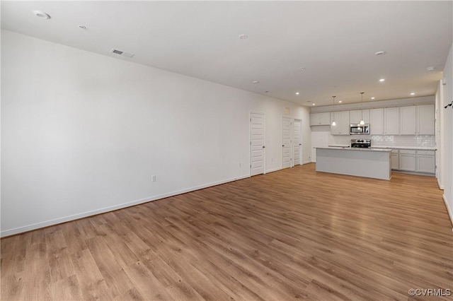 unfurnished living room with light wood-type flooring, recessed lighting, and baseboards