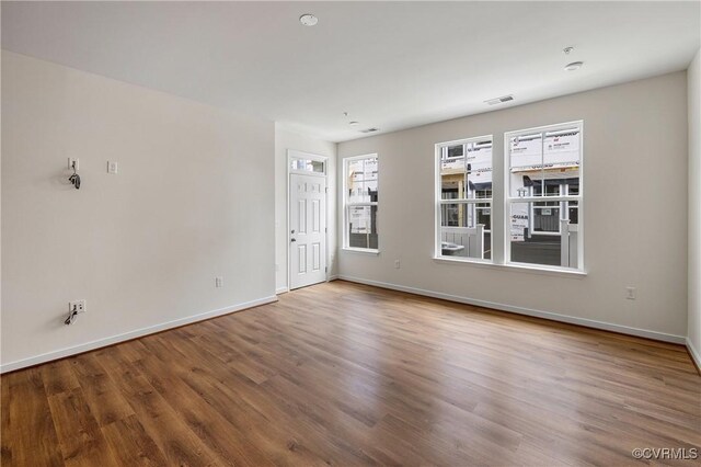 unfurnished living room with wood finished floors and baseboards