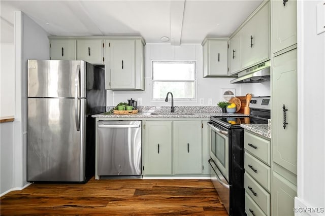 kitchen featuring appliances with stainless steel finishes, under cabinet range hood, a sink, and dark wood finished floors