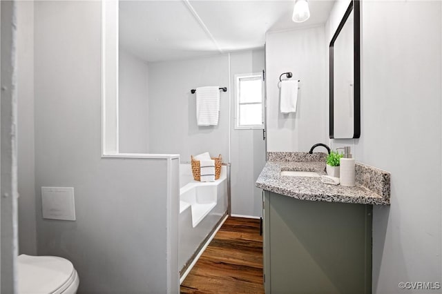 full bathroom with wood finished floors, a garden tub, toilet, and vanity