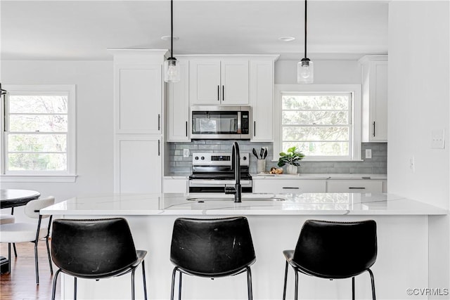kitchen with stainless steel appliances, plenty of natural light, decorative backsplash, and white cabinets