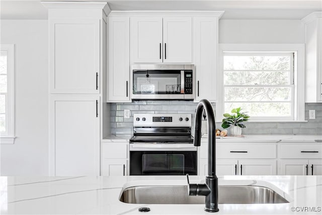 kitchen with stainless steel appliances, healthy amount of natural light, tasteful backsplash, and a sink