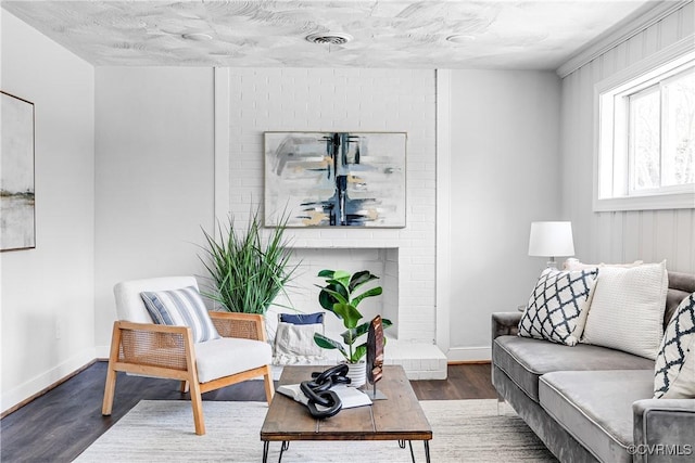 living room with wood finished floors, baseboards, and a brick fireplace