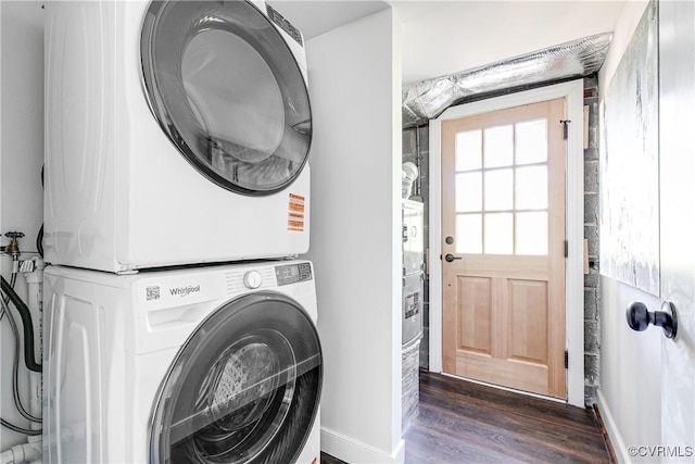 washroom with stacked washer / drying machine, dark wood finished floors, and baseboards